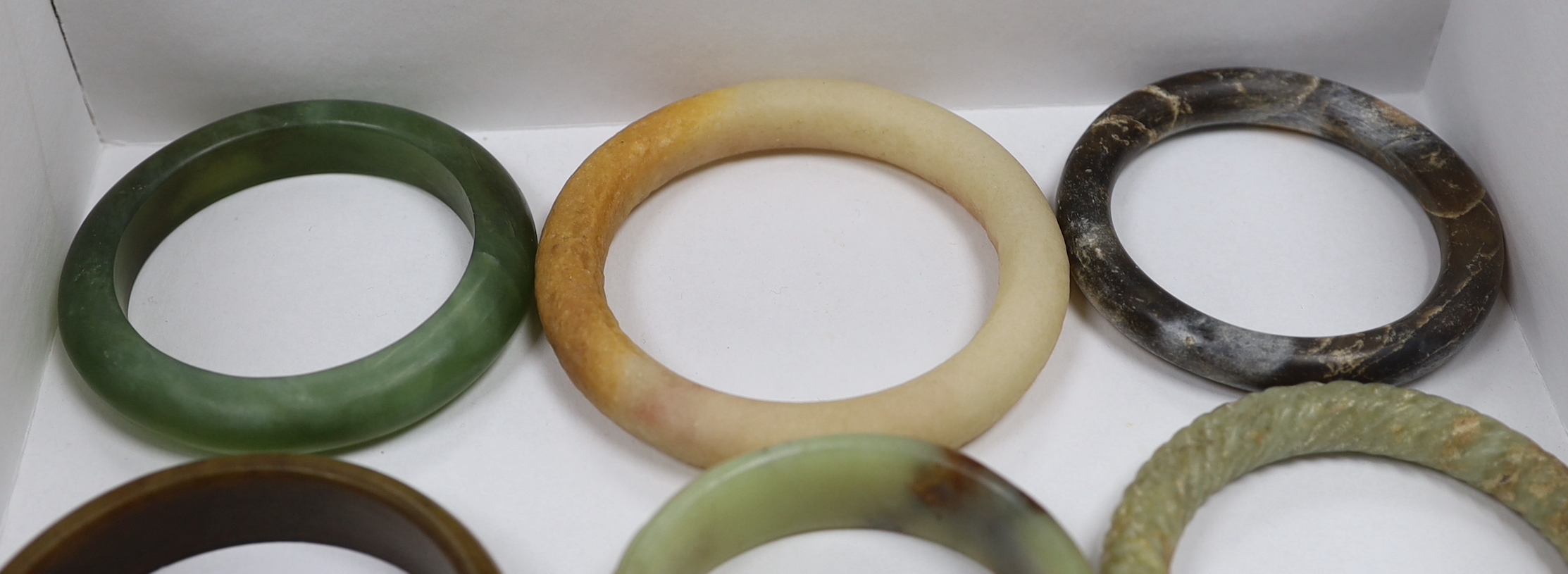 Eleven Chinese jade or hardstone bangles, largest 9cm